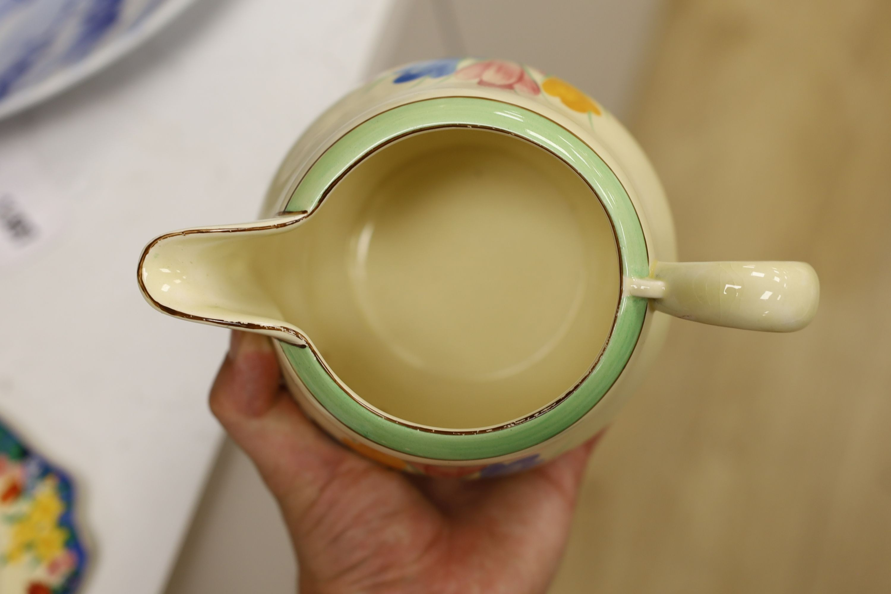 A Clarice Cliff crocus design milk jug and a Bizarre patterned side plate, jug 11.5 cms high